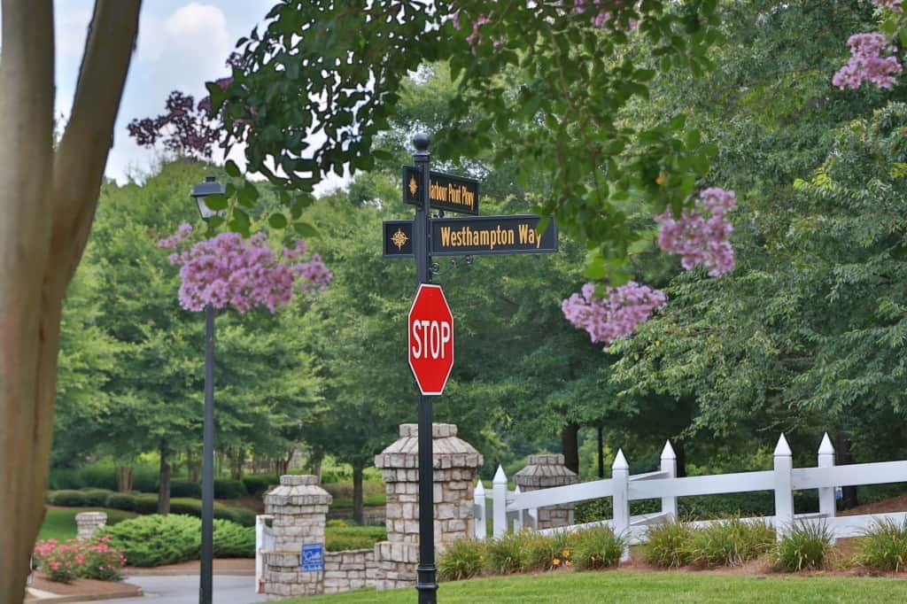 AOD decorative street signs and stop sign at a community entrance with flowering trees